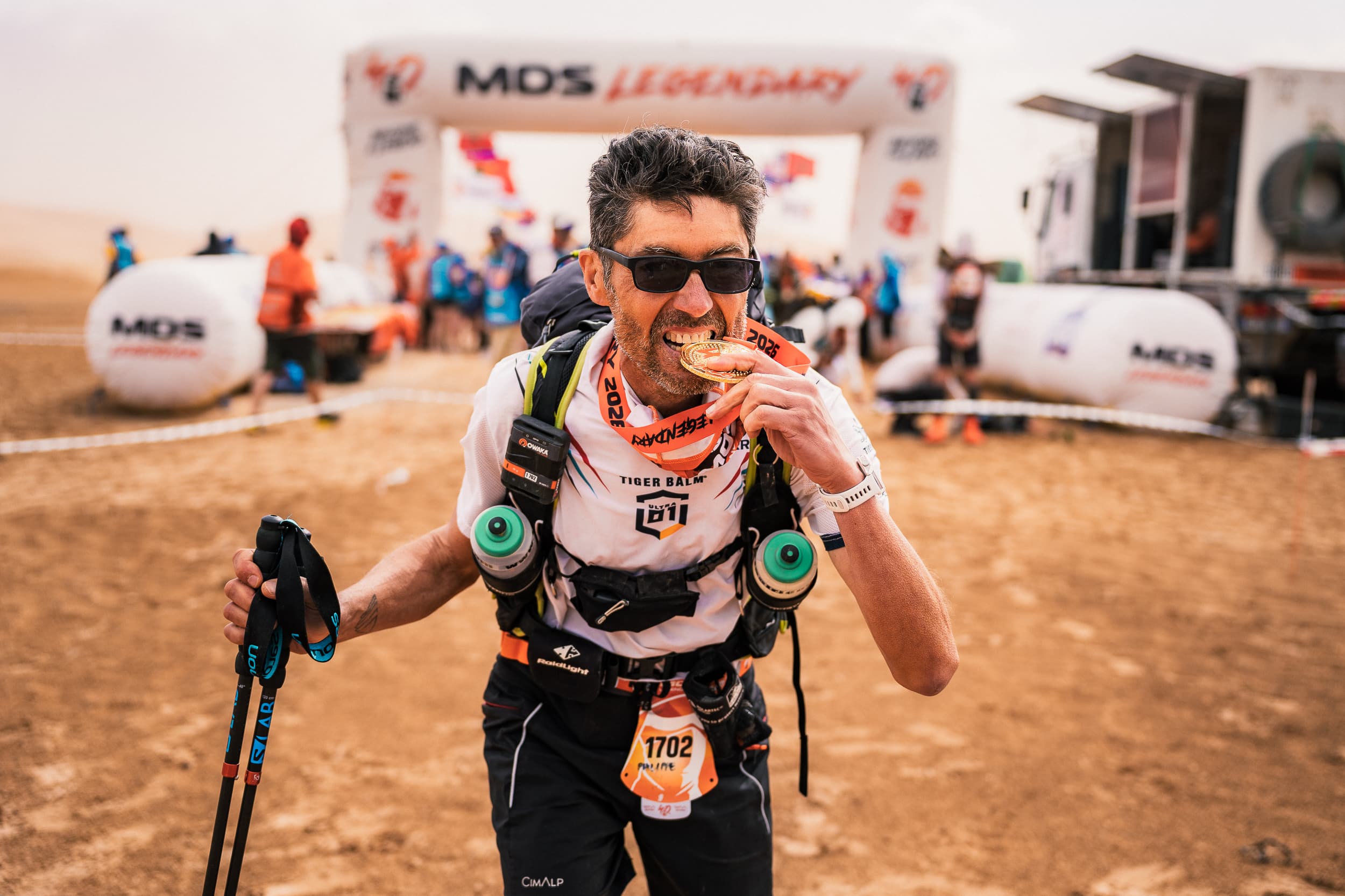 Philippe Cervasi, Finisher du Marathon des Sables Legendary, mordant sa médaille à l'arrivée dans le désert marocain
